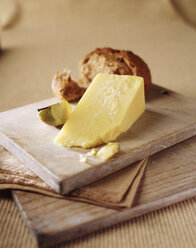 Reife Käsescheibe mit Apfelscheibe und knusprigem Vollkornbrötchen auf Holzbrettchen - CUF20370