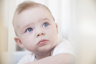 Portrait of blue eyed baby boy staring from crib - CUF20394