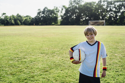 Junge mit deutschem Fußballtrikot, der einen Fußball hält, lizenzfreies Stockfoto