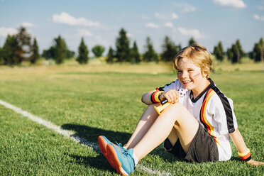 Boy wearing German soccer shirt, blowing horns on soccer field - MJF02317