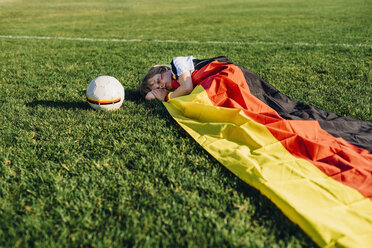 Schlafender Junge auf Fußballplatz, bedeckt mit deutscher Flagge - MJF02326