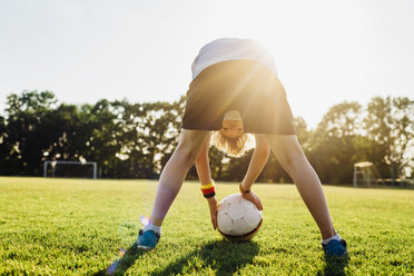 Boy on soccer field, bending over, looking through his legs - MJF02336