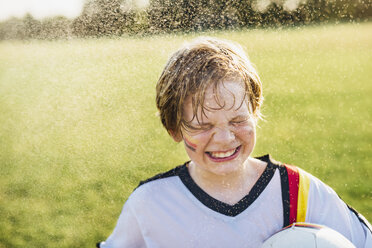 Junge im deutschen Fußballtrikot steht im Wasser und spritzt - MJF02344