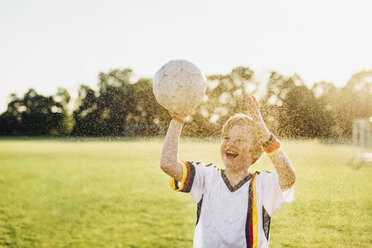 Junge mit deutschem Fußballtrikot, der vor Freude schreit und in Wasserspritzern steht - MJF02346