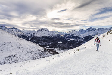 Mann geht auf verschneitem Berg, Rückansicht, Engadin, Schweiz - CUF20547