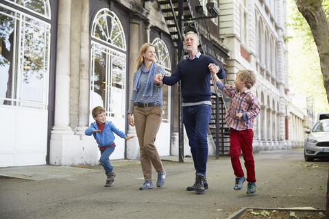 Familie geht auf der Straße und hält sich an den Händen, lizenzfreies Stockfoto