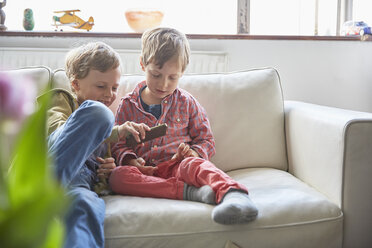 Boys sitting on sofa looking at smartphone - CUF20606