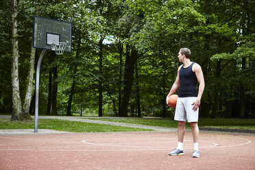 Junger männlicher Basketballspieler, der über seine Schulter auf den Basketballkorb schaut - CUF20670