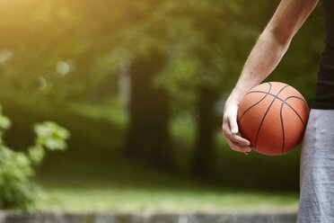 Cropped detail of young male basketball player holding ball - CUF20672