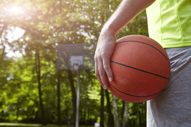 Cropped close up of young male basketball player holding ball - CUF20676