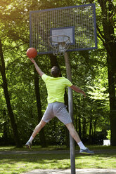 Rückansicht eines jungen männlichen Basketballspielers, der springt und den Ball auf den Basketballkorb wirft - CUF20677