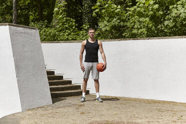 Porträt eines selbstbewussten jungen männlichen Basketballspielers, der einen Ball hält - CUF20679