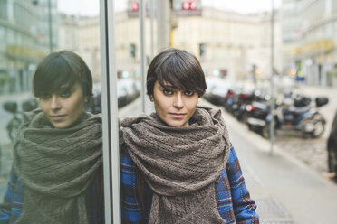 Porträt einer jungen Frau, die sich an ein Fenster lehnt, im Freien - CUF20718