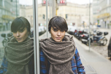 Portrait of young woman leaning against window, outdoors - CUF20718