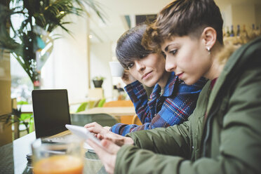 Zwei Schwestern im Café, die ein digitales Tablet benutzen - CUF20754