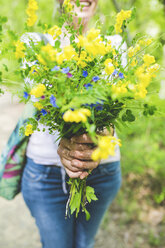 Abgeschnittene Aufnahme einer Frau, die einen Strauß frischer gelber Wildblumen im Garten hält - CUF20811