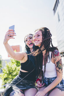 Zwei junge Frauen machen ein Smartphone-Selfie in einer Wohnsiedlung - CUF20830