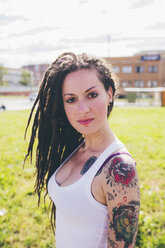 Portrait of tattooed young woman in urban park - CUF20842