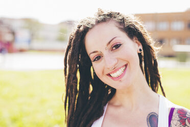 Portrait of tattooed young woman with dreadlocks in urban park - CUF20843