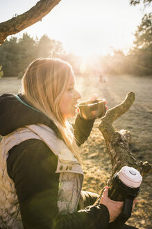 Frau entspannt sich und trinkt Kaffee auf einer Baumkrone, Augsburg, Bayern, Deutschland - CUF20855