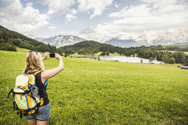 Woman taking photograph of Karwendel mountains, Gerold, Bavaria, Germany - CUF20858