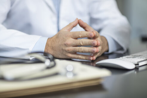 Akten und Stethoskop auf dem Schreibtisch einer Arztpraxis und in den Händen eines Arztes - ZEF15507