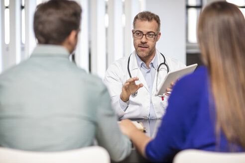 Doctor talking to couple in medical practice - ZEF15519