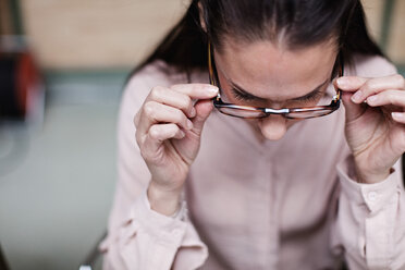 Nahaufnahme einer Geschäftsfrau, die eine Brille trägt, während sie im Büro sitzt - MASF07683