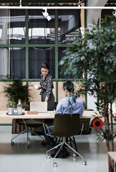 Businesswoman having coffee and using laptop while standing by coworker at table - MASF07690