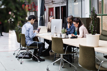 Business coworkers using technologies at table in office meeting - MASF07702