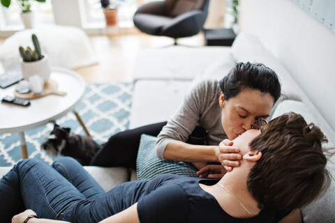 Hohe Winkel Ansicht der lesbischen Paar küssen, während auf dem Sofa im Wohnzimmer sitzen, lizenzfreies Stockfoto