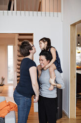 Smiling family enjoying while standing in living room at home - MASF07733