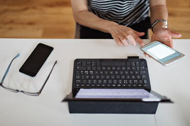 Midsection der mittleren erwachsenen Frau mit Laptop und Smartphone am Tisch - MASF07755