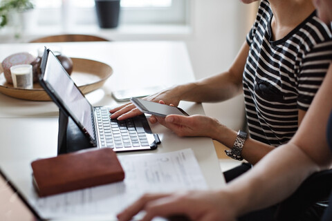 Midsection of woman using digital tablet and mobile phone while sitting with girlfriend at table stock photo