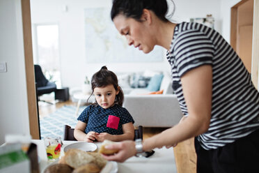 Girl looking at mother serving food on table - MASF07784