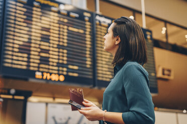 Seitenansicht einer Geschäftsfrau mit Blick auf die Ankunft-Abflug-Tafel im Flughafen - MASF07798