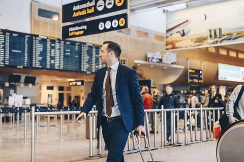 Älterer Geschäftsmann mit Gepäck zu Fuß im Flughafen-Terminal, lizenzfreies Stockfoto