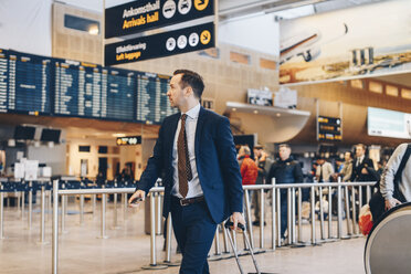 Älterer Geschäftsmann mit Gepäck zu Fuß im Flughafen-Terminal - MASF07802