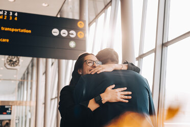 Smiling businesswoman embracing businessman at airport terminal - MASF07826