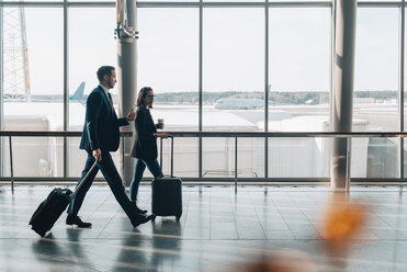 Full length of business couple with luggage communicating in airport - MASF07828