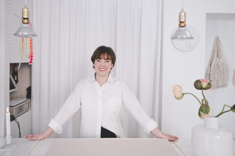 Porträt einer lächelnden Innenarchitektin am Schreibtisch im Studio, lizenzfreies Stockfoto