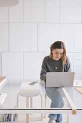 Junge Unternehmerin mit Laptop am Schreibtisch im Designstudio - MASF07887