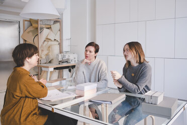 Female design professionals having discussion at desk in workshop - MASF07897