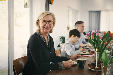 Porträt einer lächelnden Großmutter, die mit ihrer Familie bei einer Party am Tisch sitzt - MASF07918