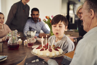 Junge bläst Kerzen auf Geburtstagskuchen aus, während er mit seiner Familie zu Hause feiert - MASF07920