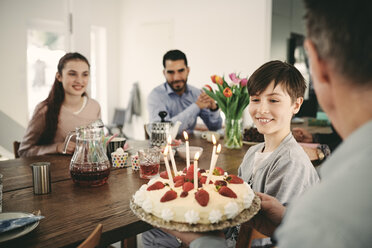 Junge sieht sich Geburtstagskuchen an, während er mit seiner Familie zu Hause sitzt - MASF07924