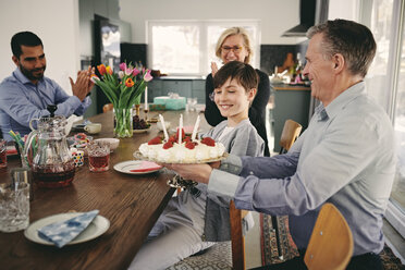 Smiling boy with grandparents and father with birthday cake at table - MASF07930