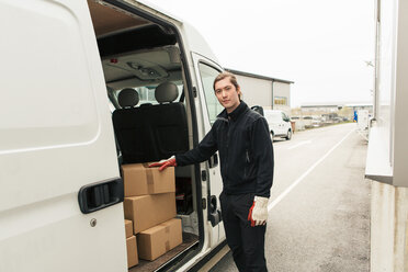 Confident manual worker standing by stack of boxes in delivery van - MASF07965