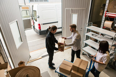 High angle view of male coworkers delivering boxes while female is using digital tablet - MASF07976