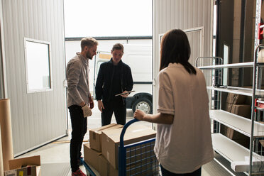 Female and male coworkers analyzing boxes against delivery van - MASF07978